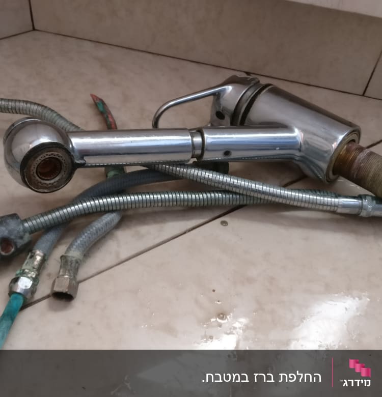 ברז וכמה צינורות מתכת על רצפה רטובה